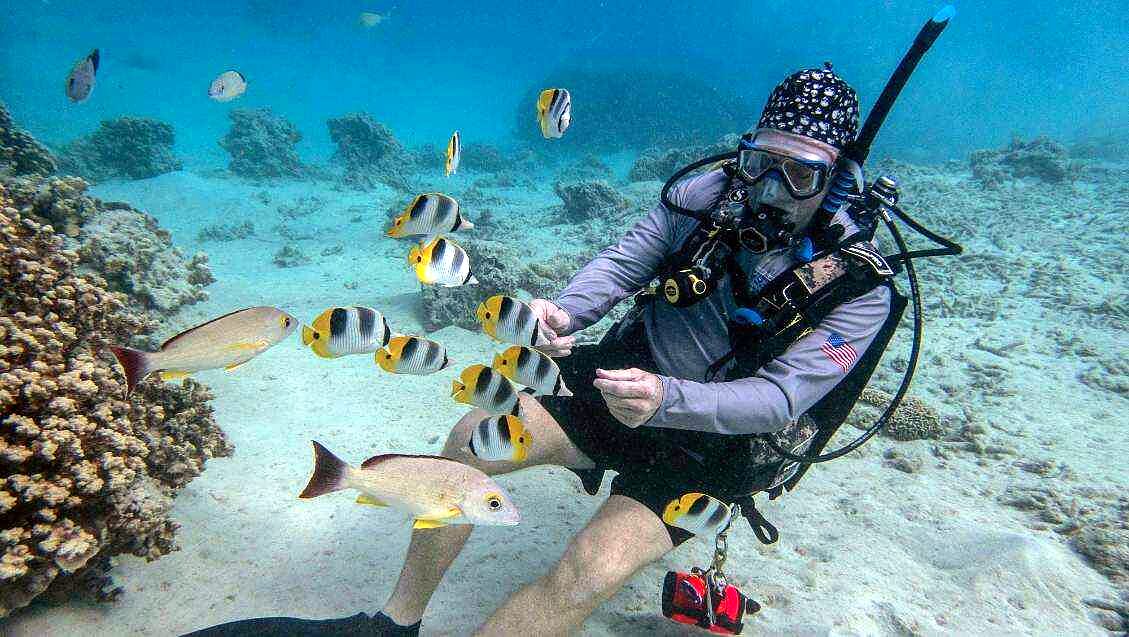 Ron surrounded by butterflyfish on a reef